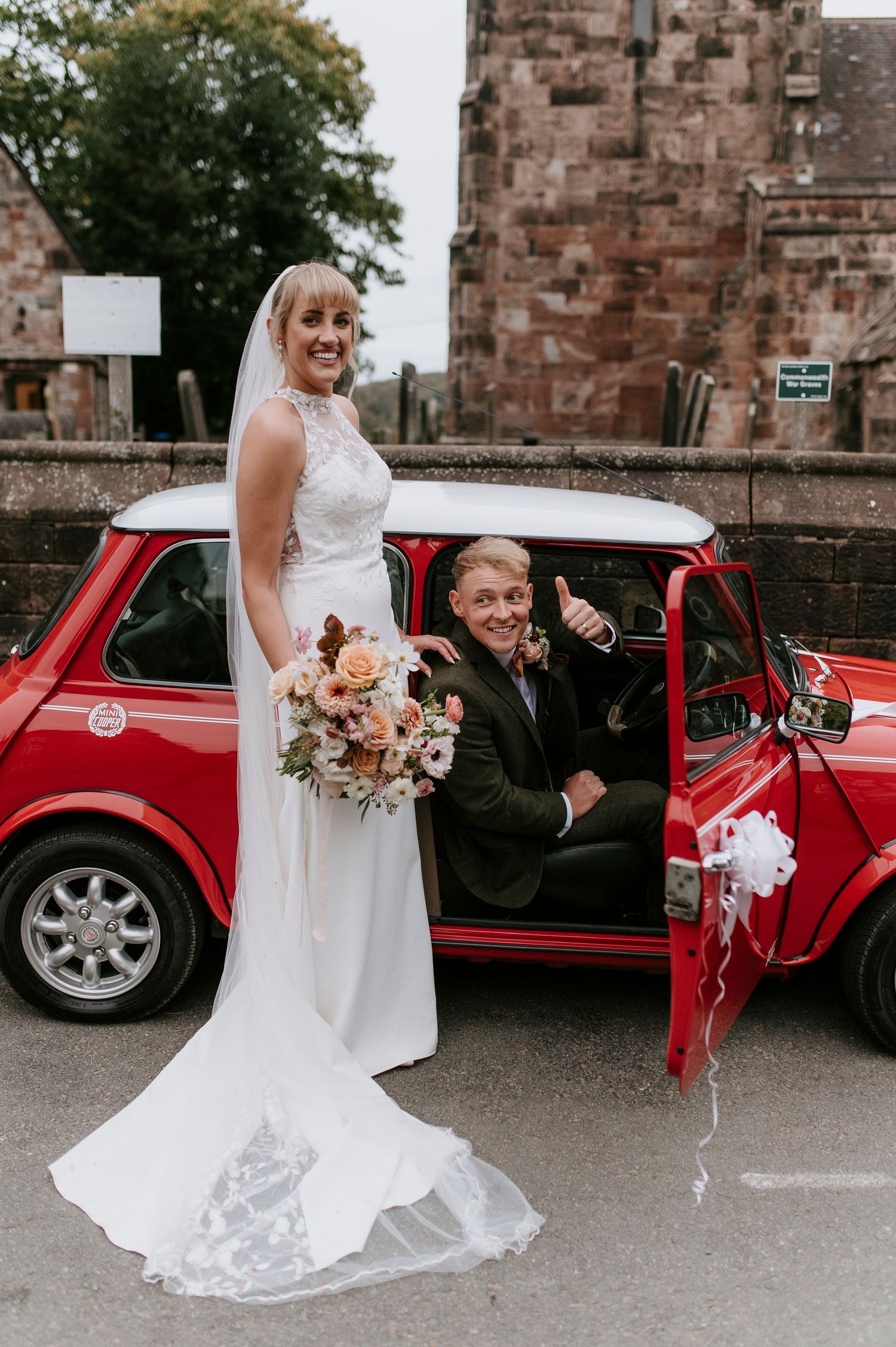 Classic red vintage car serves as elegant wedding day transportation at stone castle venue.