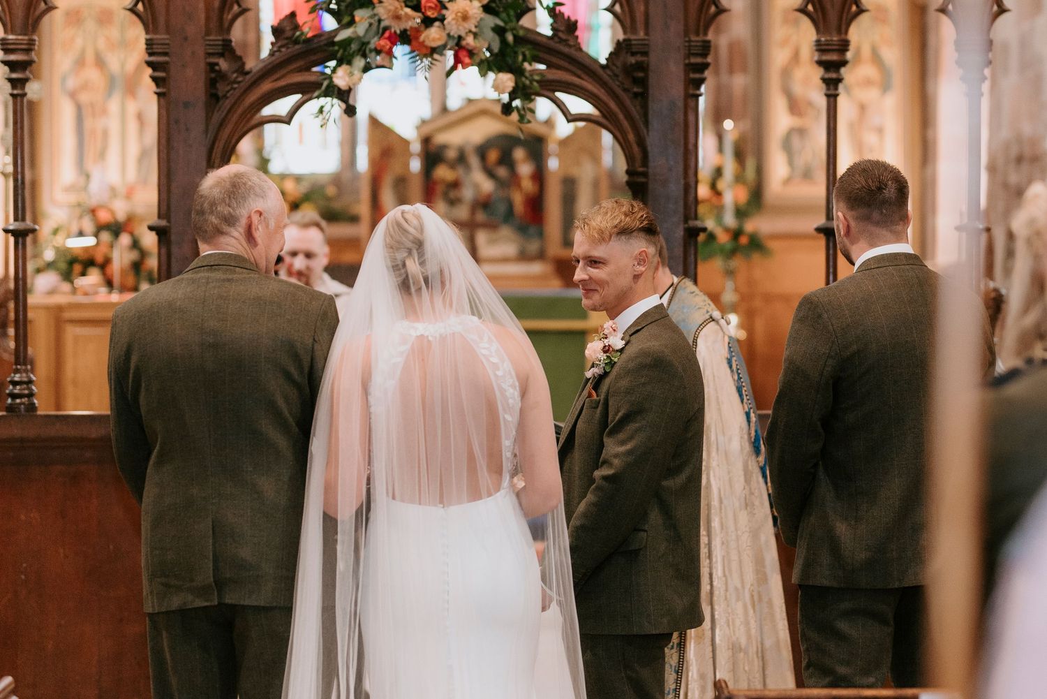 A bride and groom stand at the altar during a traditional church wedding ceremony with elegant wooden pews.