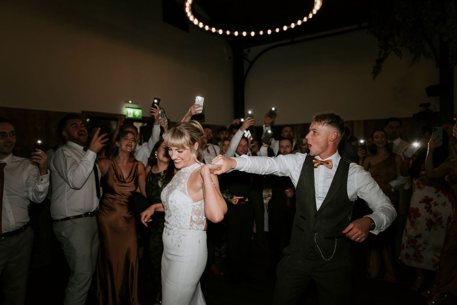 Wedding guests dancing and celebrating on a dark dance floor at a reception party.