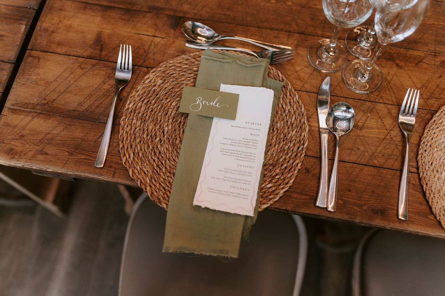 Rustic wooden table setting with wine glasses and place settings at an elegant restaurant or event venue.