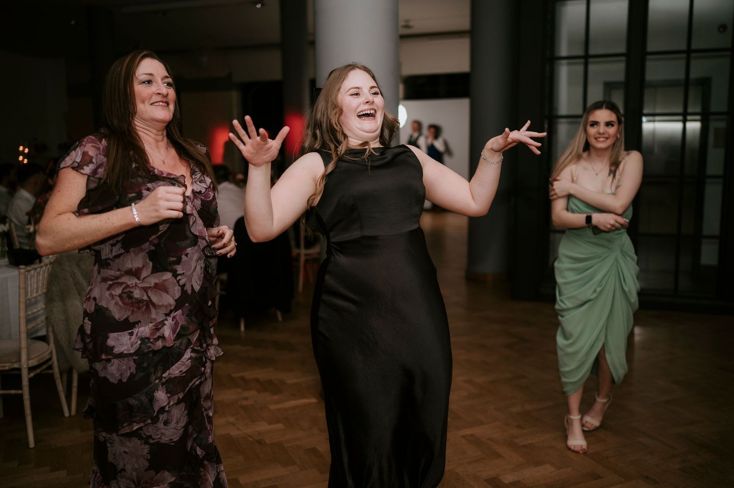 Wedding guests dancing and celebrating on the dance floor at an indoor reception venue.