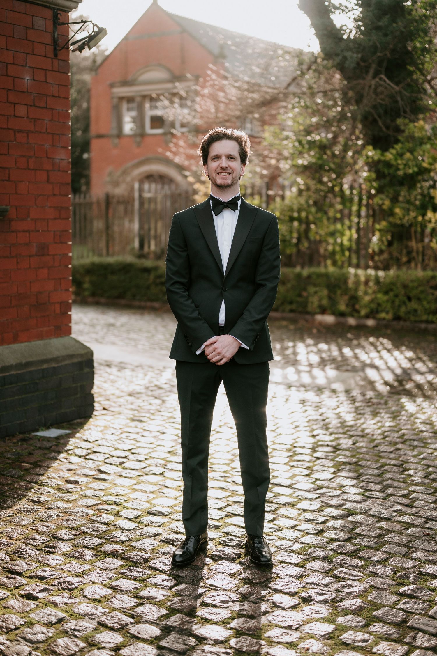 A series of photos showing someone in a tuxedo standing on wet cobblestone pavement.