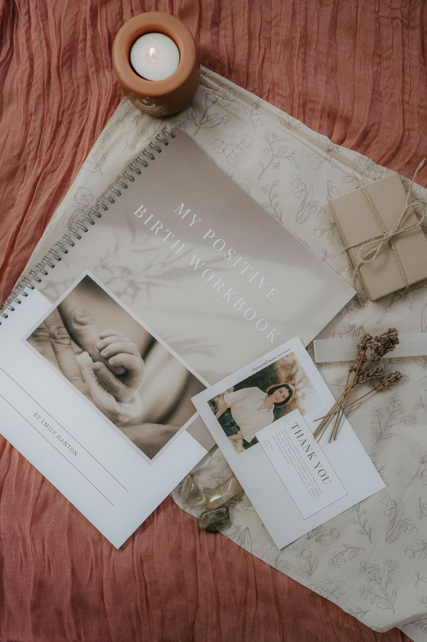 Minimalist wedding stationery layout with white cards, candle and dried flowers on pink linen fabric background.