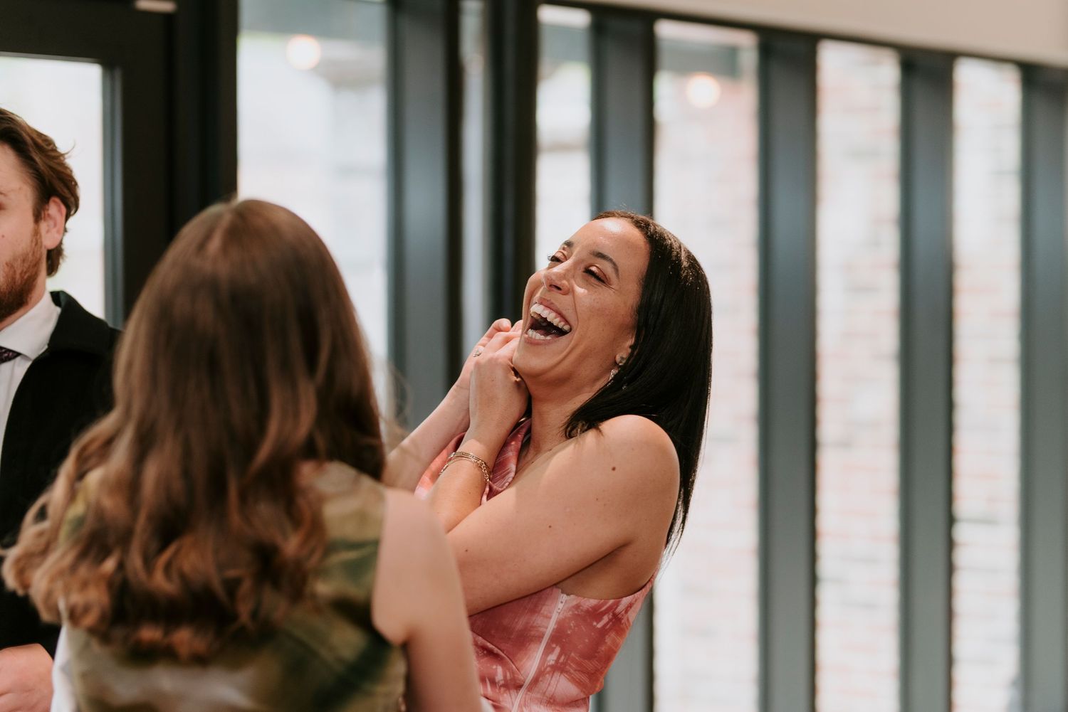 A couple shares a joyful moment together while laughing in a bright interior space.
