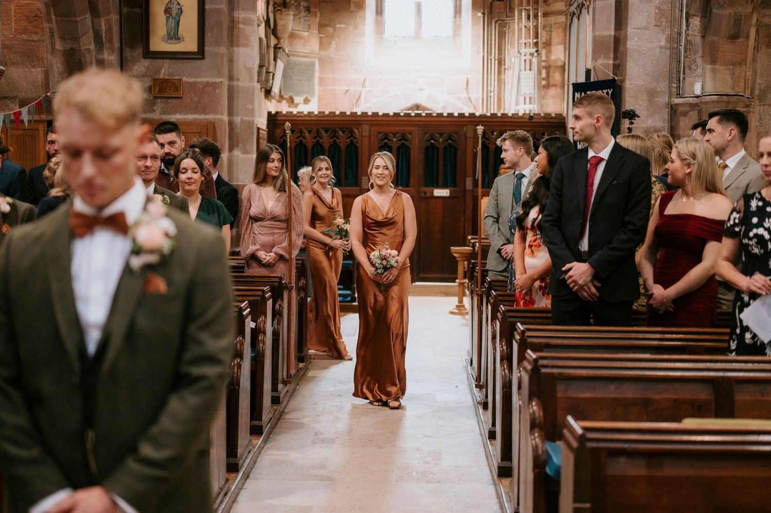 Romantic wedding ceremony in a rustic wooden church with warm lighting and guests seated in wooden pews.
