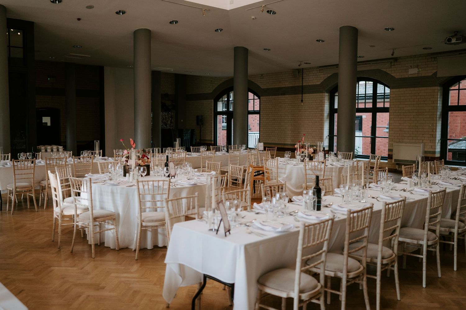 Modern wedding reception venue with white tablecloths and chairs set up for an elegant celebration.