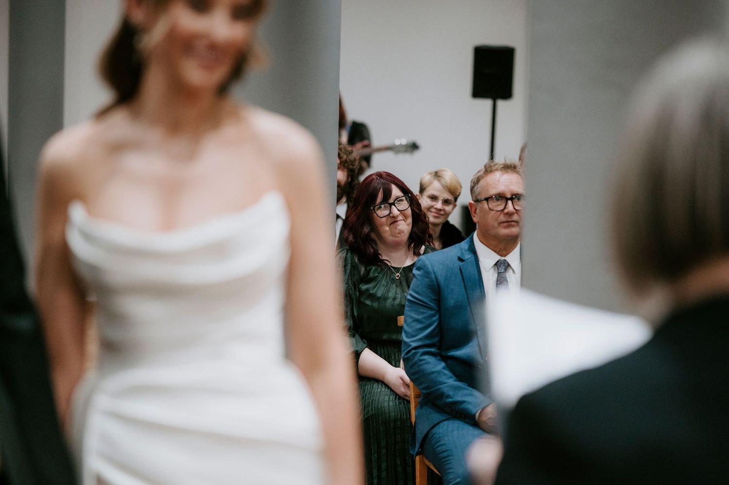 Wedding guests gather in a bright indoor venue during a celebration ceremony.