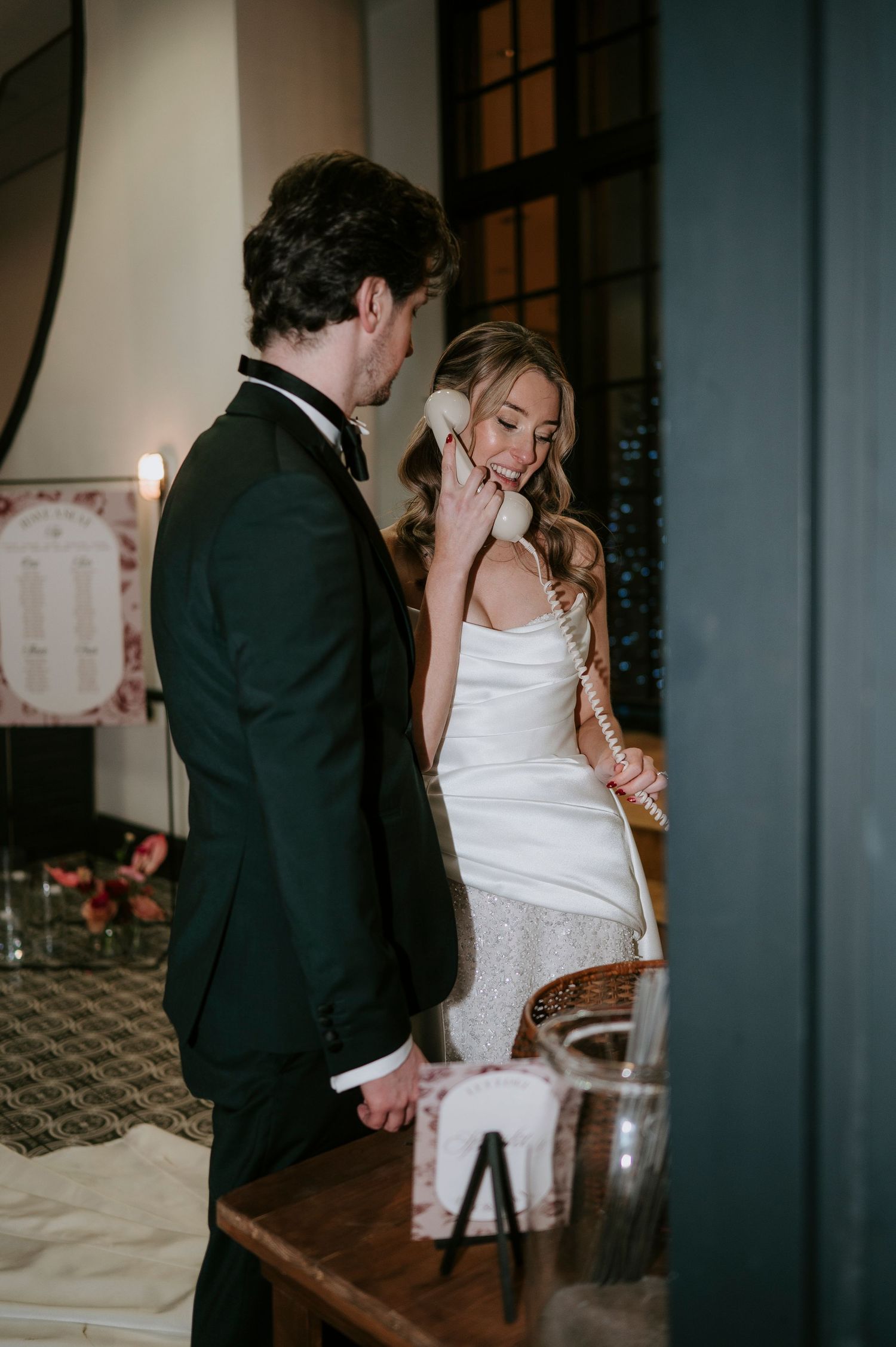 Wedding reception scene with couple dancing near rustic wooden table.