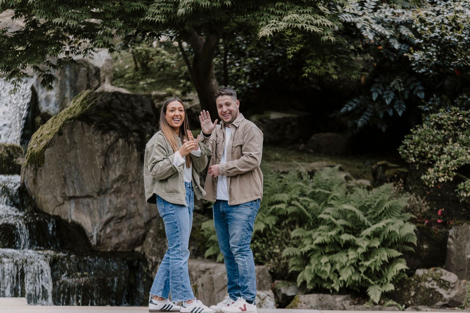 A happy couple celebrating their engagement in front of a cascading waterfall.