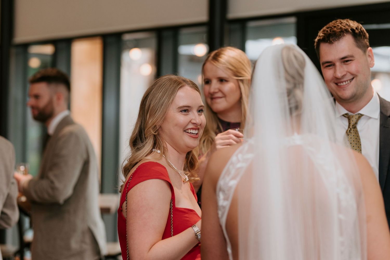 A group of wedding guests in formal attire share a joyful moment during a celebration.