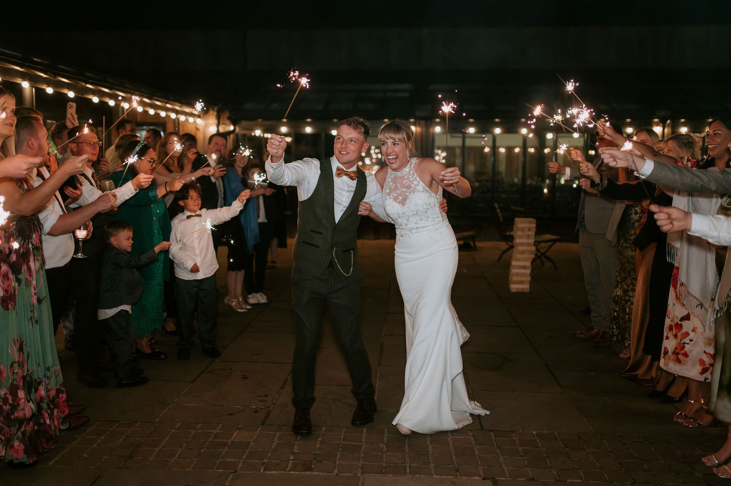 Wedding guests hold sparklers in the dark to create a magical nighttime exit for the newlyweds on their special day.