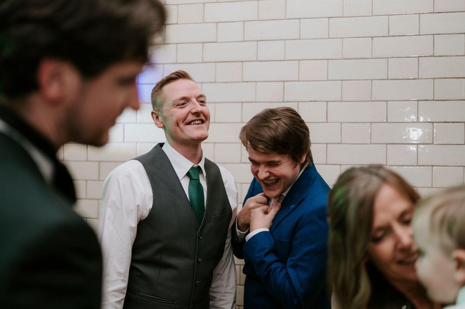 Wedding guests enjoying celebration against white brick wall background.