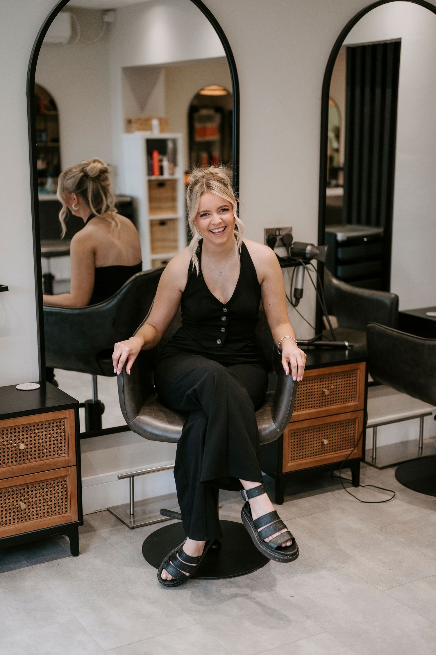 A series of photos showing someone sitting on a wooden cane chair wearing black clothing and sandals.