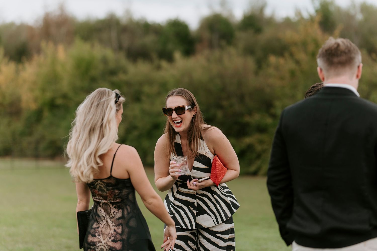 Wedding party walks together through a grassy field on a sunny autumn day.