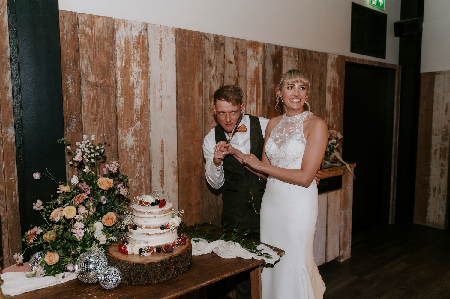 A bride and groom share a romantic dance together in a rustic wooden barn venue with soft lighting.