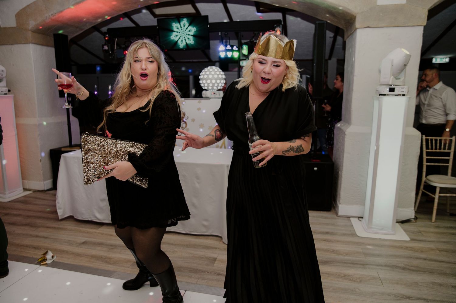 People dancing and enjoying themselves at a wedding reception in an elegant indoor venue with white decor.