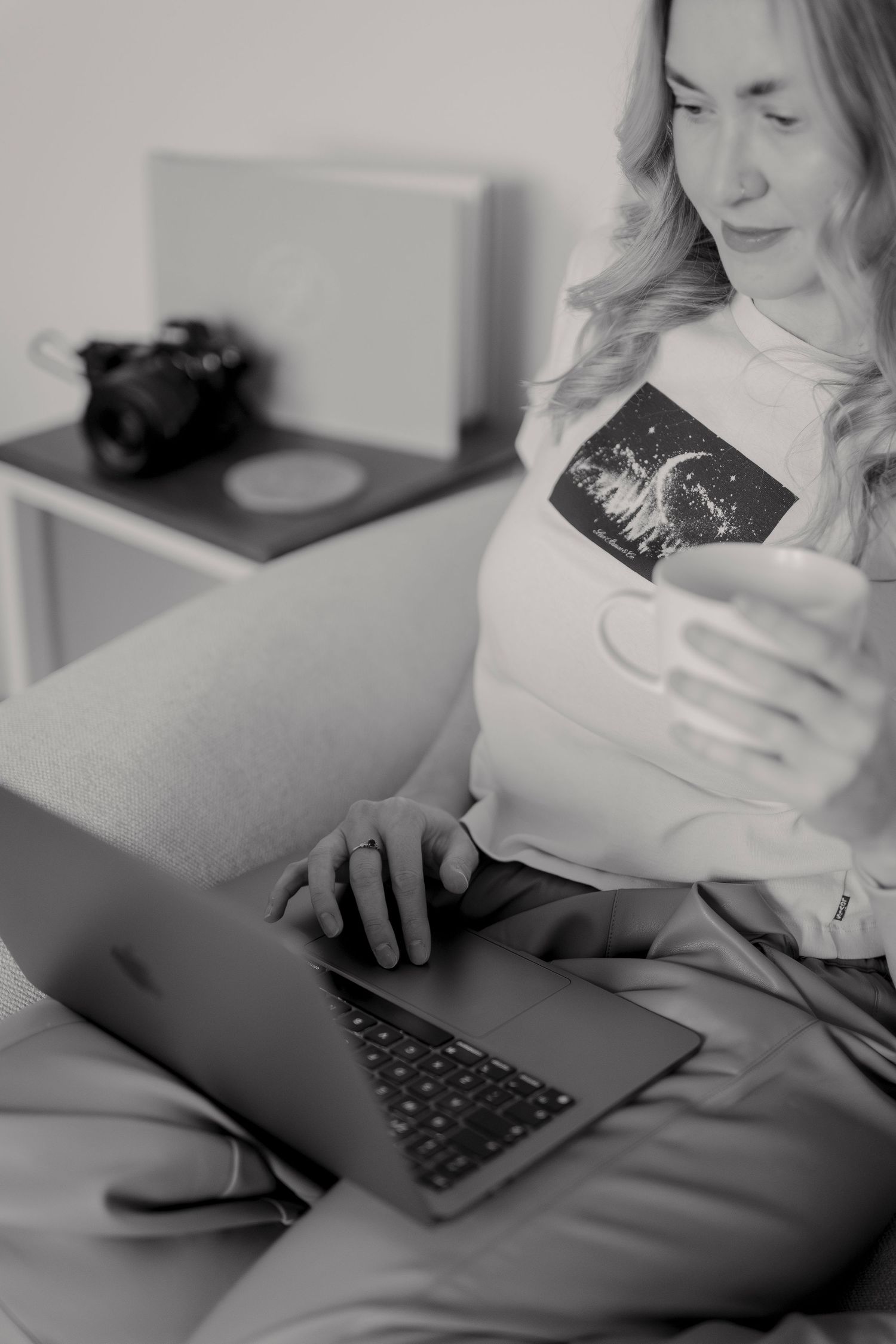 A person uses a laptop computer while relaxing on a couch in black and white tones.