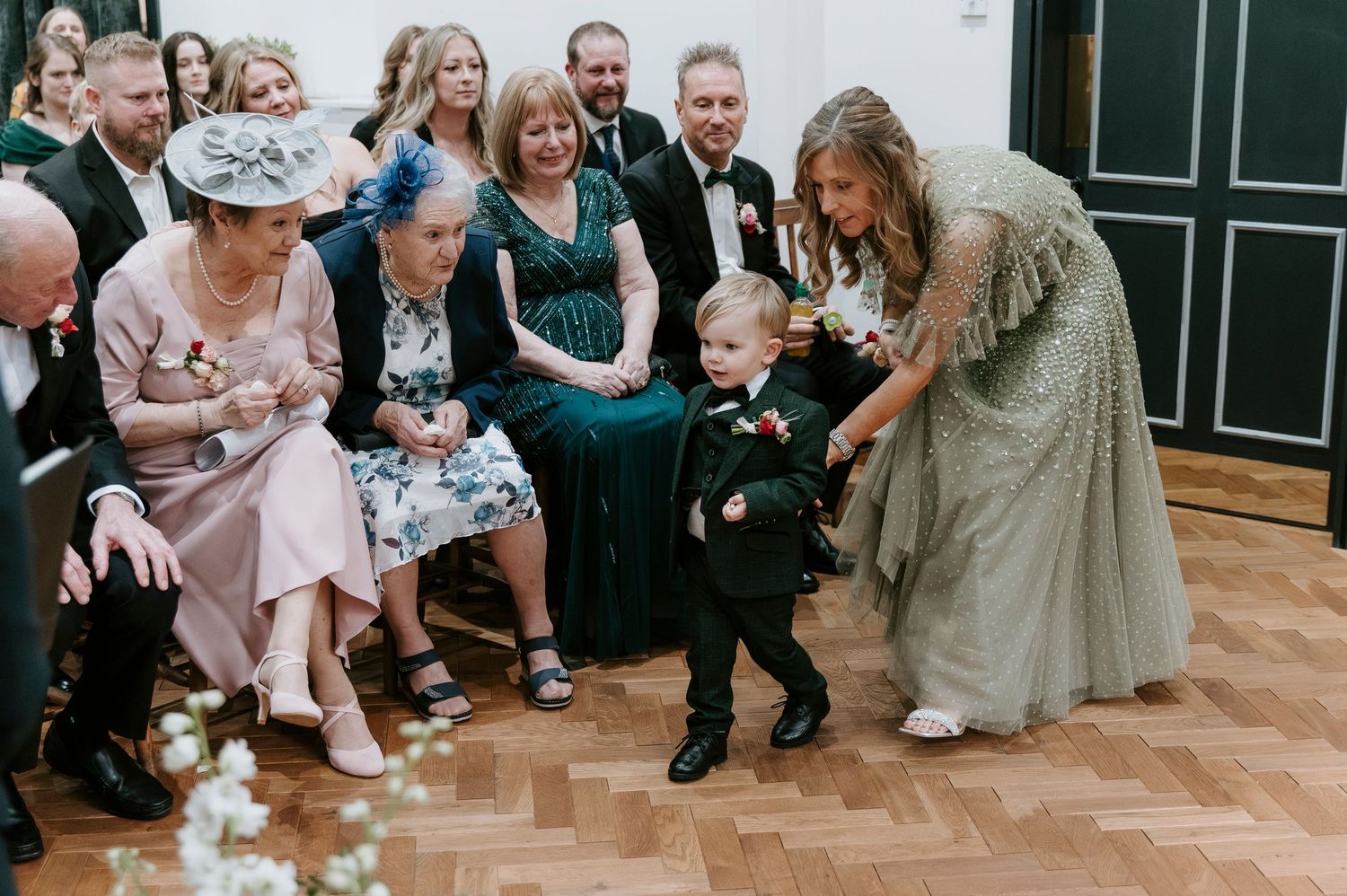 Wedding guests dance and celebrate together on a wooden dance floor during a joyful reception party.