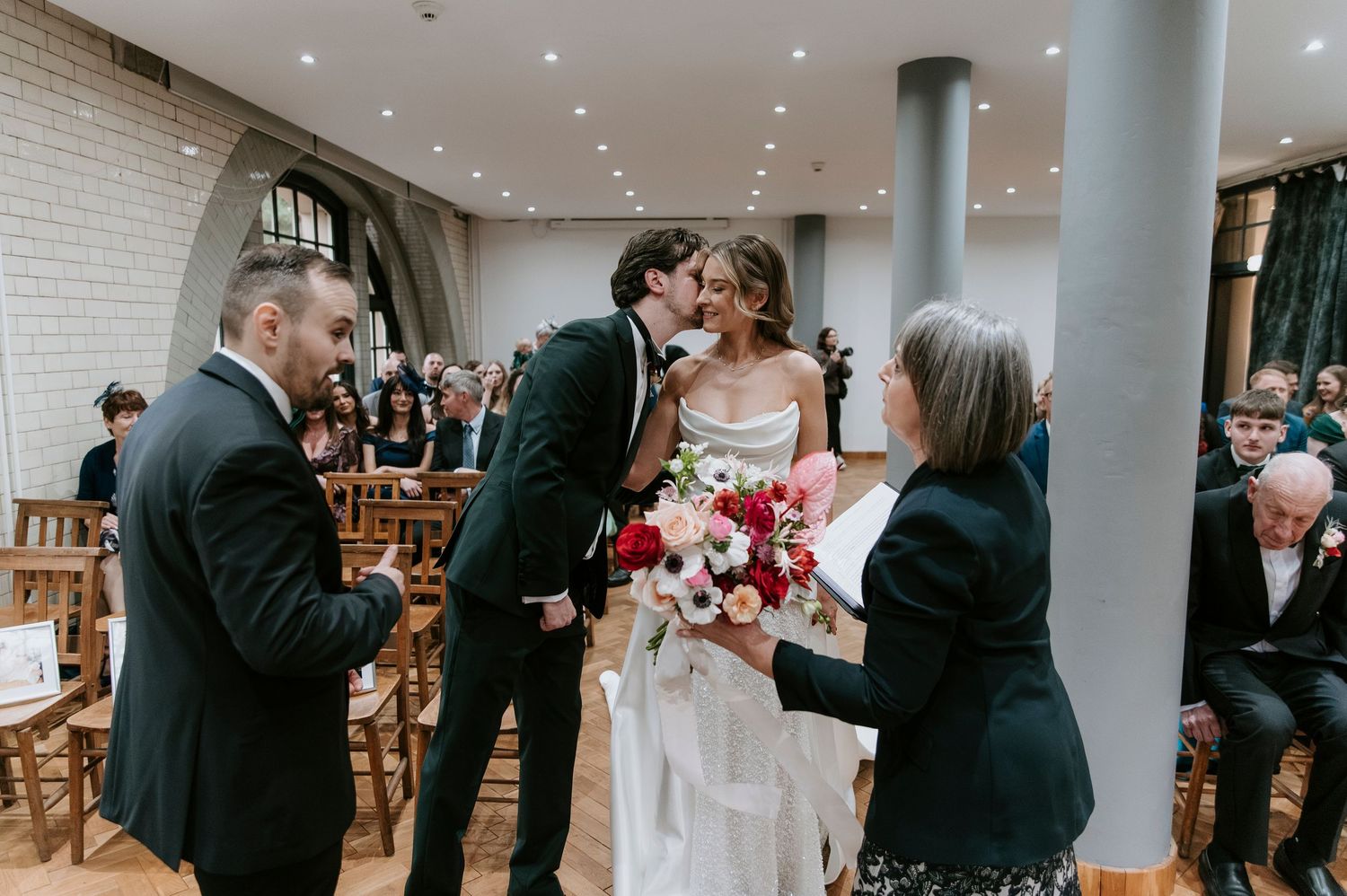 A joyful wedding ceremony moment in a modern venue with white brick walls and elegant decor.