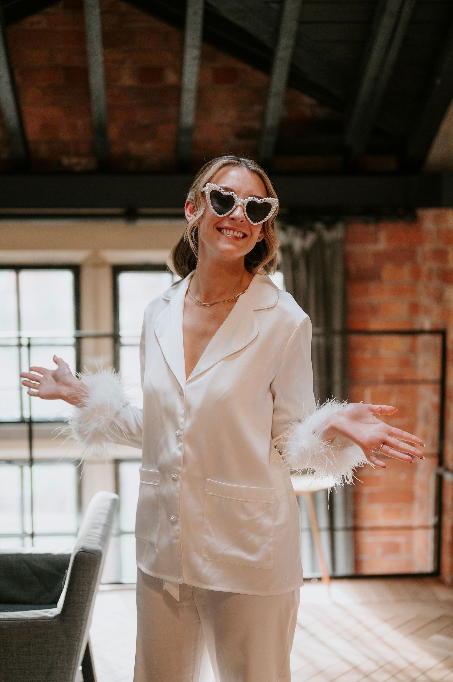 Candid shots of someone in an elegant white outfit dancing joyfully in a brick-walled room with natural lighting.