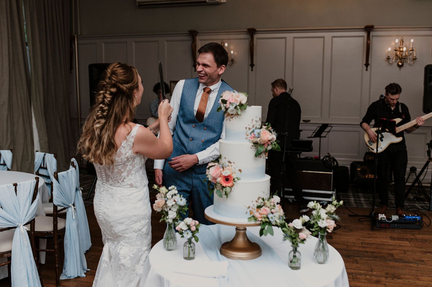 Wedding reception venue decorated with elegant white floral centerpieces and chandeliers.