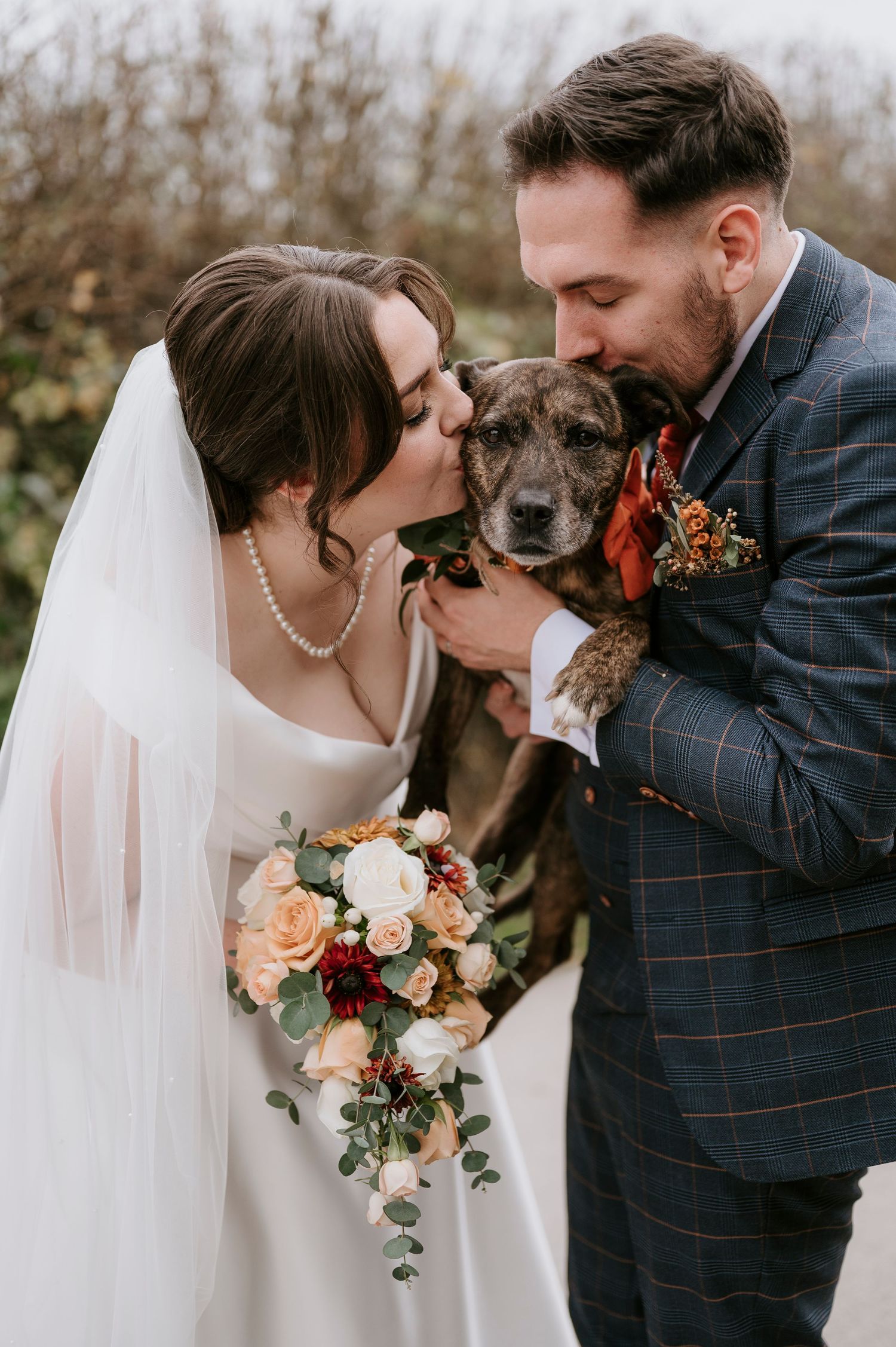 A romantic wedding photo series featuring a couple and their beloved dog in autumn with peach and burgundy florals.
