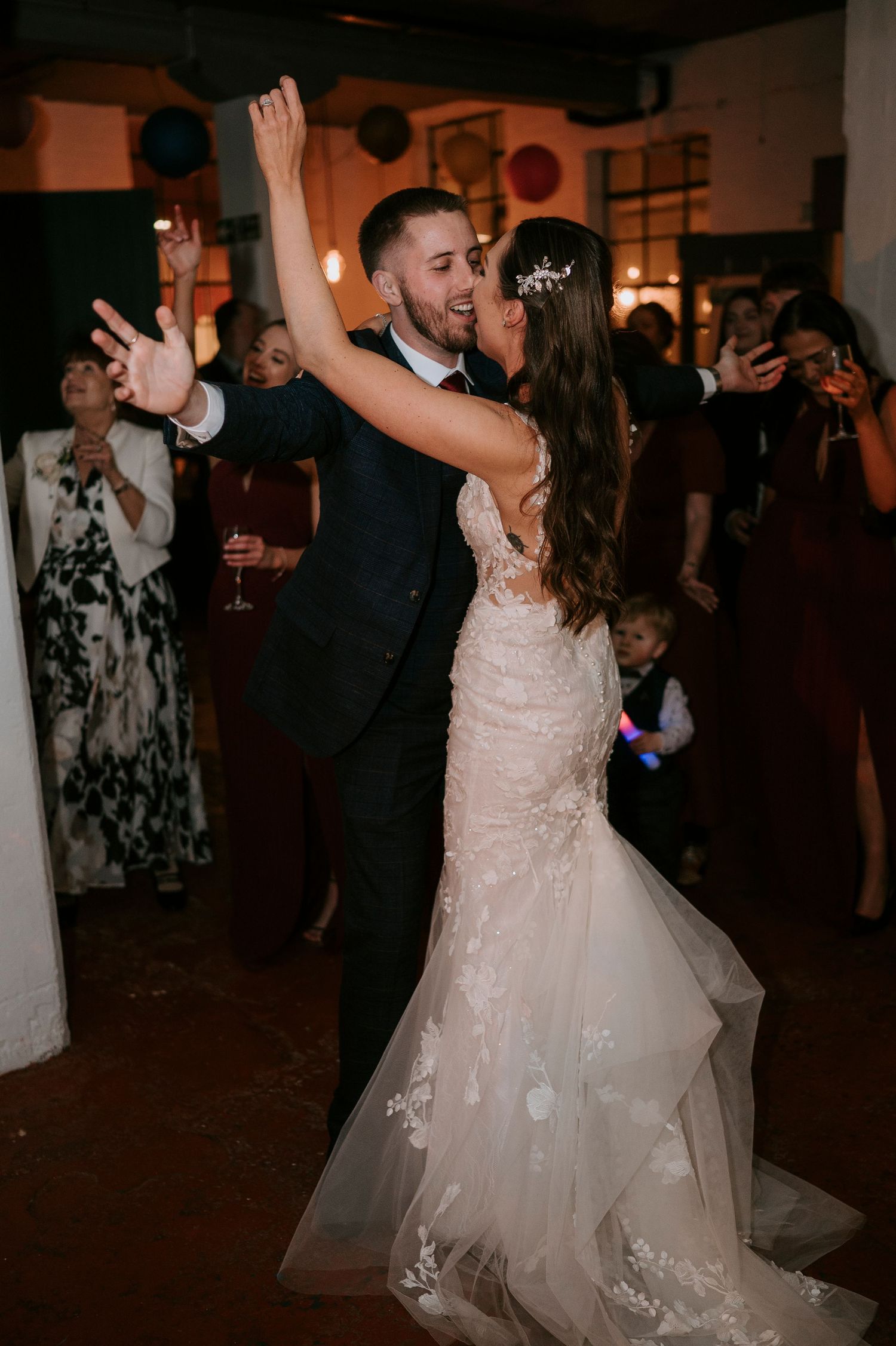 Bride and groom dancing closely together surrounded by guests at evening wedding reception.