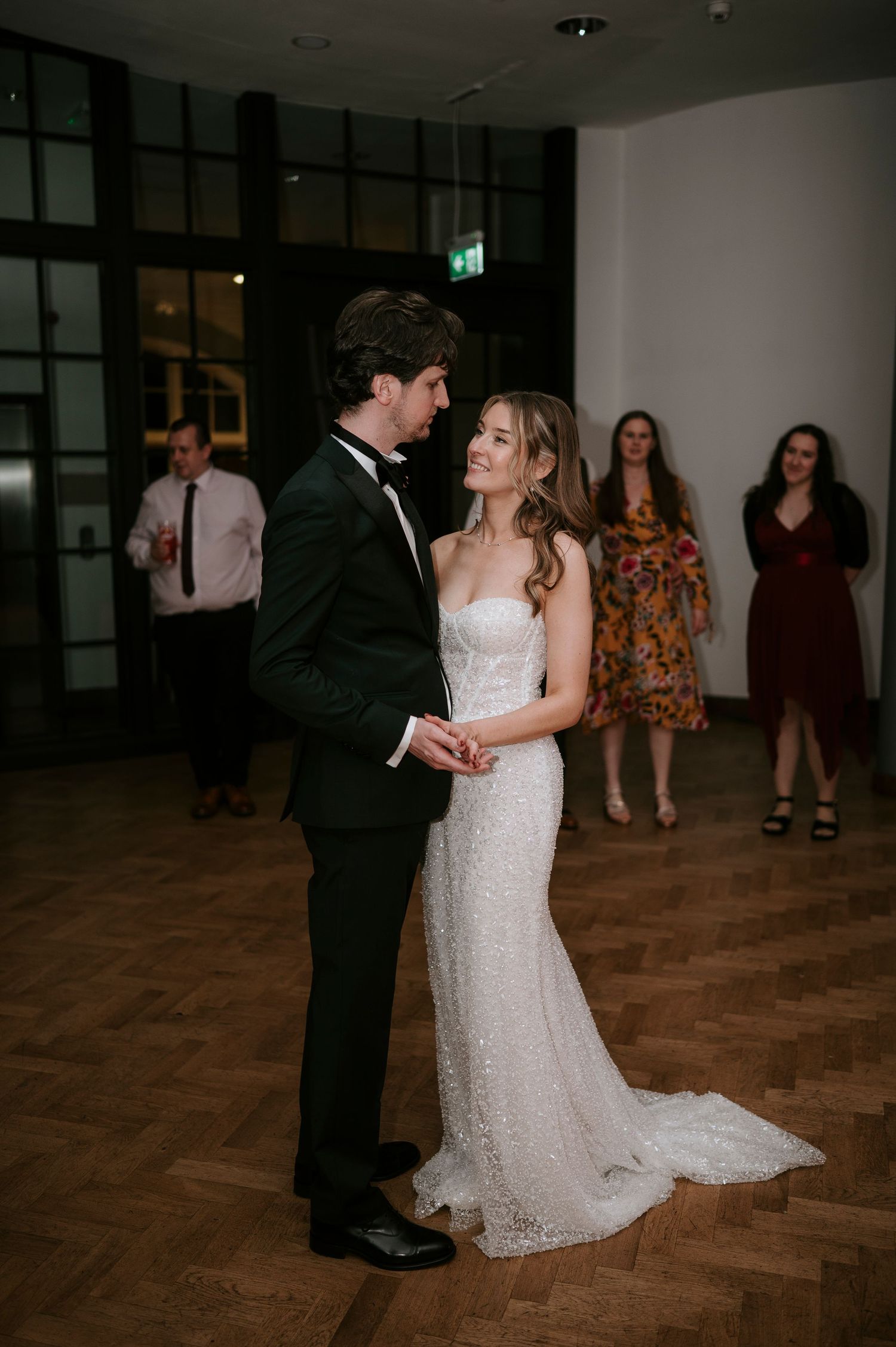 A couple dances together at their wedding reception, with the bride wearing a beautiful lace gown.