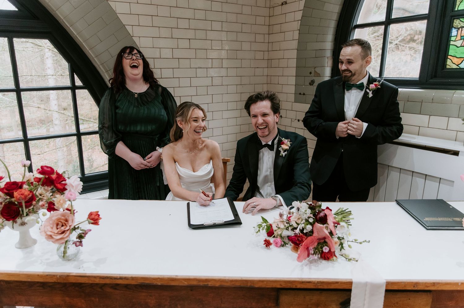 Guests celebrate at a modern wedding reception with brick walls and arched windows.