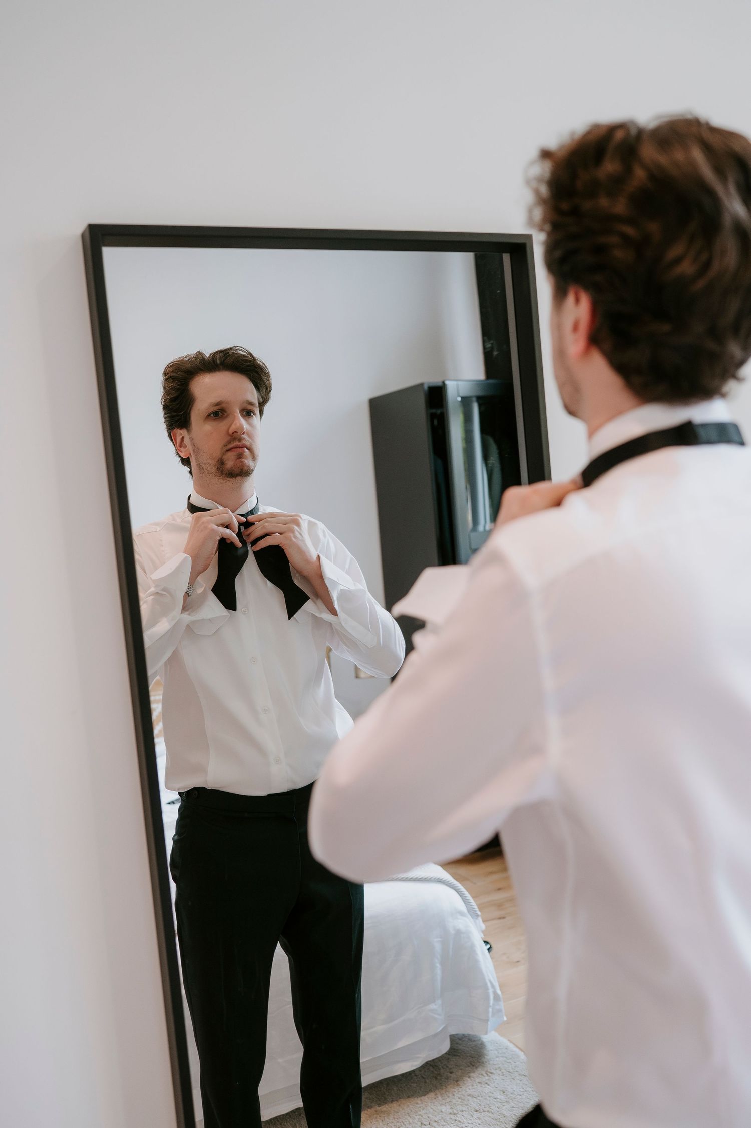 A sequence of photos showing someone adjusting their tie and getting ready in front of a mirror.
