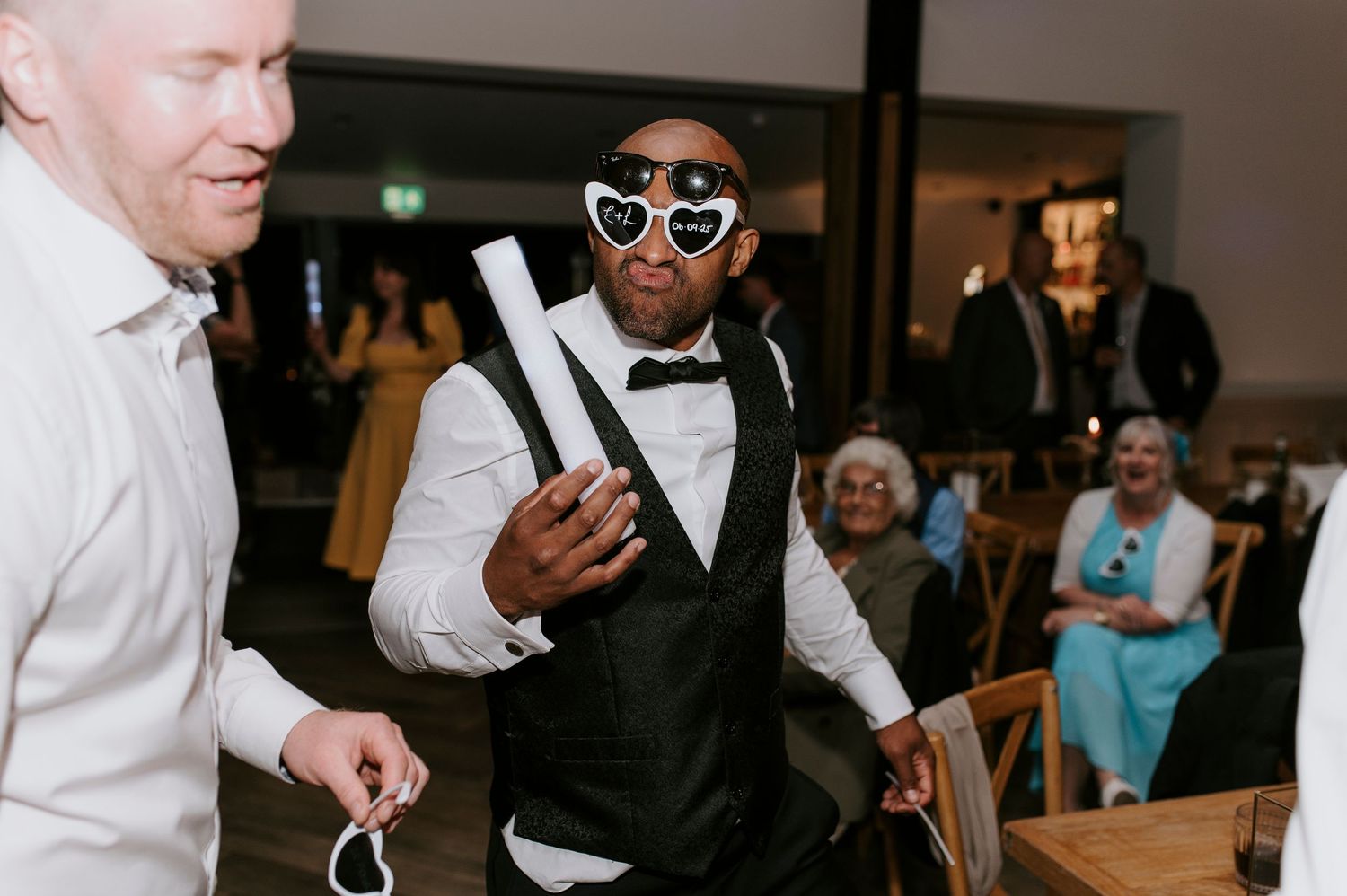 People in formal attire dancing and celebrating at a wedding reception party.