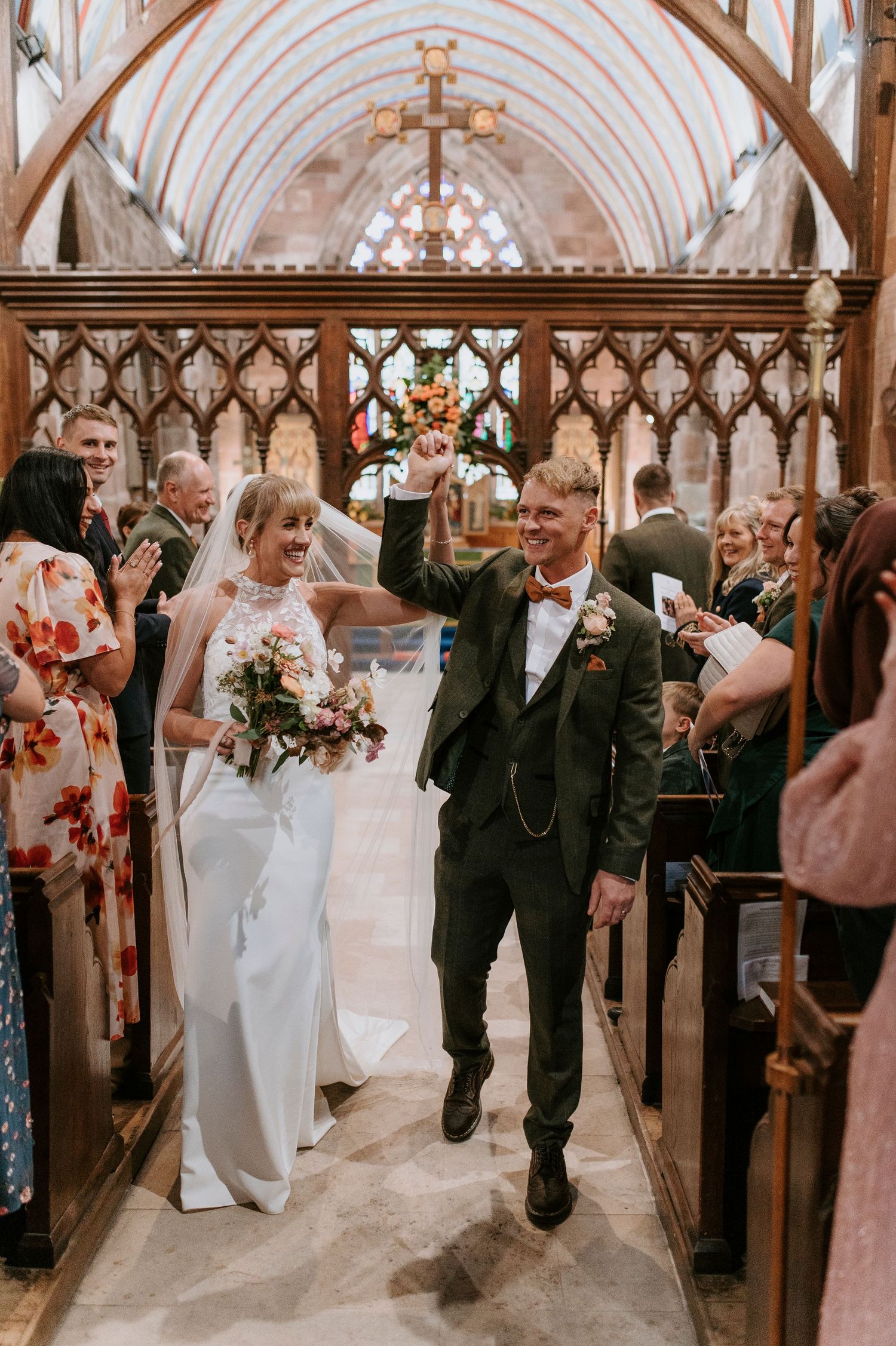 Wedding party celebrates in a historic church with vaulted ceilings and ornate wooden archways.