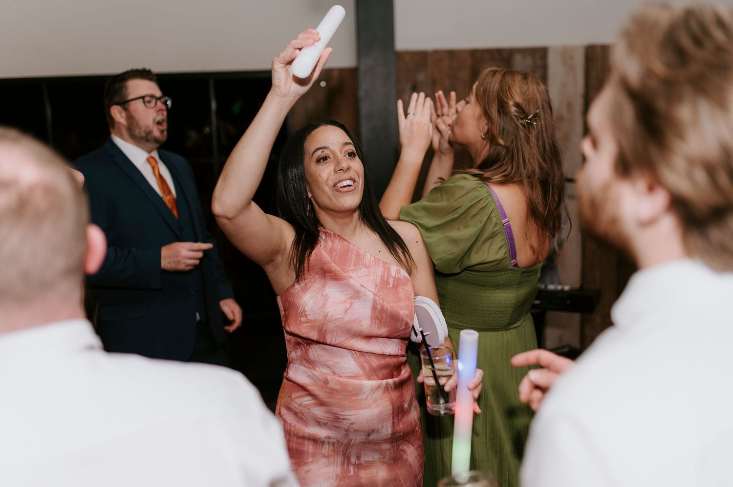 Wedding guests dance and celebrate together on the dance floor at an indoor reception venue.