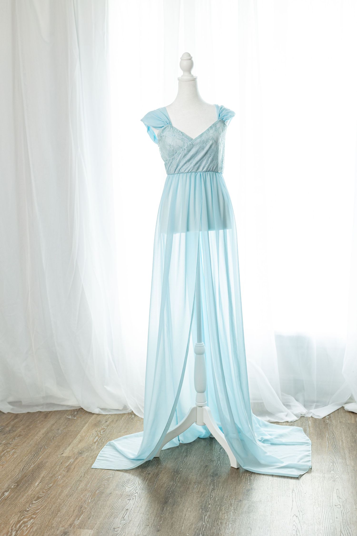 Elegant light blue chiffon maternity gown with lace bodice and flowing skirt displayed on a mannequin.