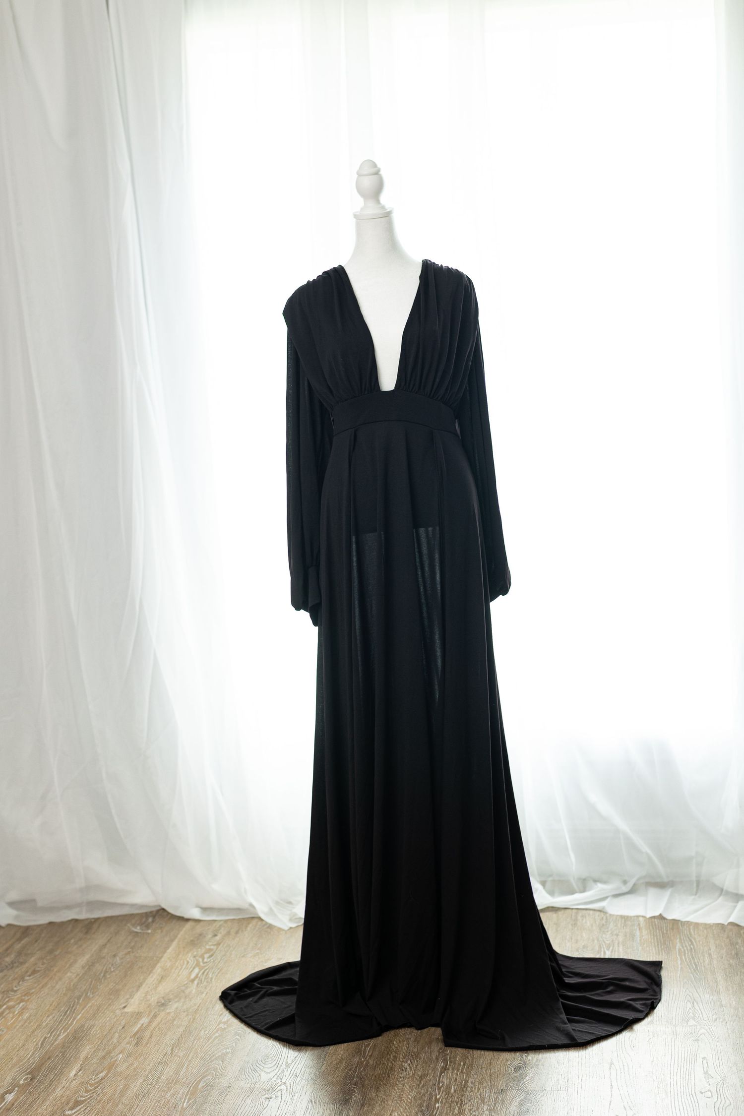 Elegant black deep V-neck long sleeve maxi gown with flowing train displayed on a mannequin.