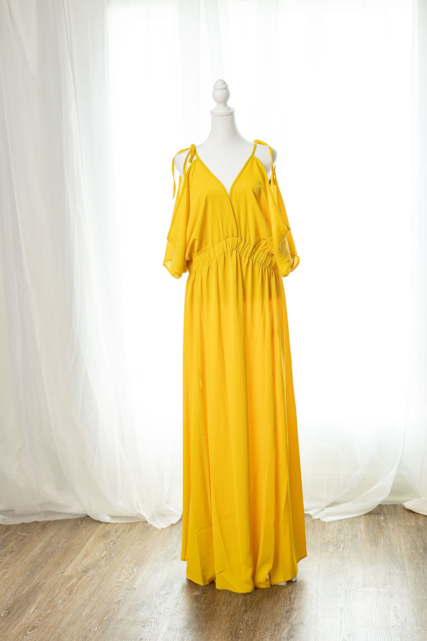 Yellow maxi dress with cold shoulder design and V-neckline on a white mannequin.