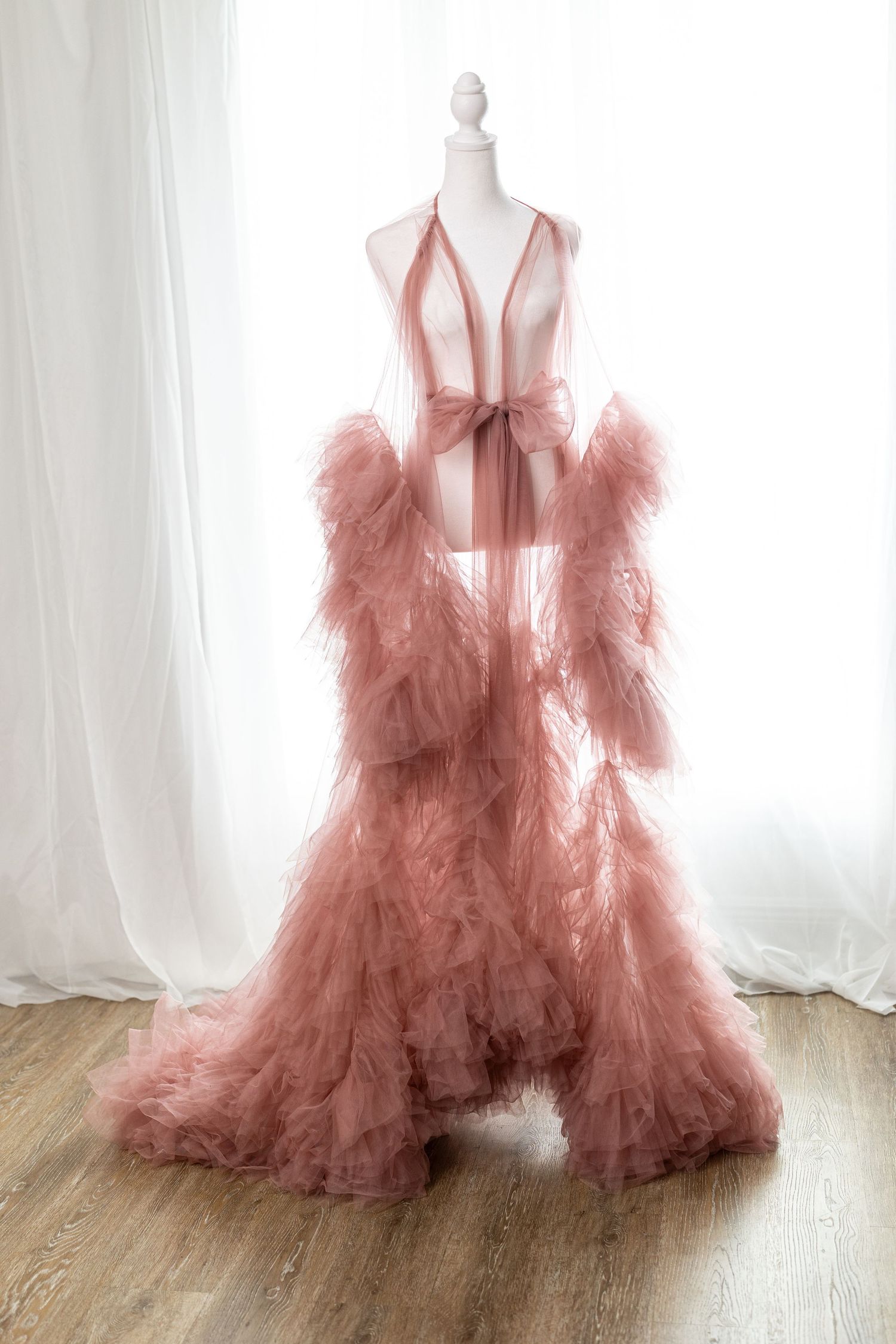 Elegant dusty rose tulle robe gown with ruffled sleeves and deep V-neck displayed on a mannequin.