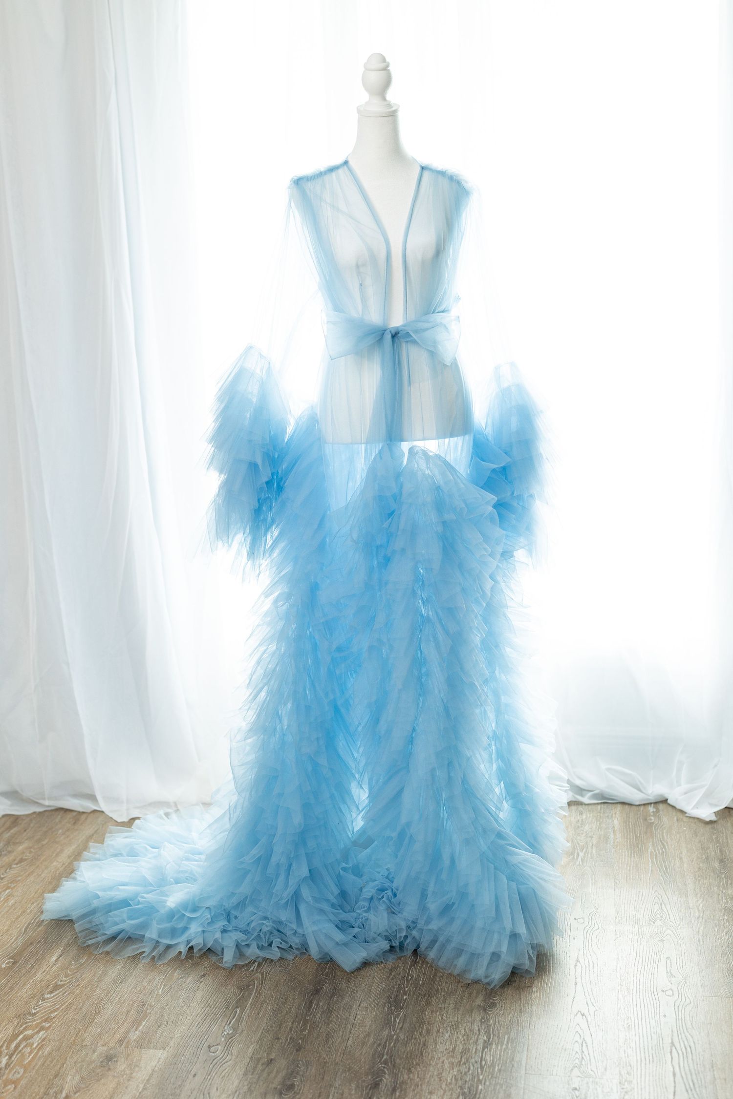 Elegant light blue tulle robe with ruffled sleeves and train displayed on a dress form mannequin.