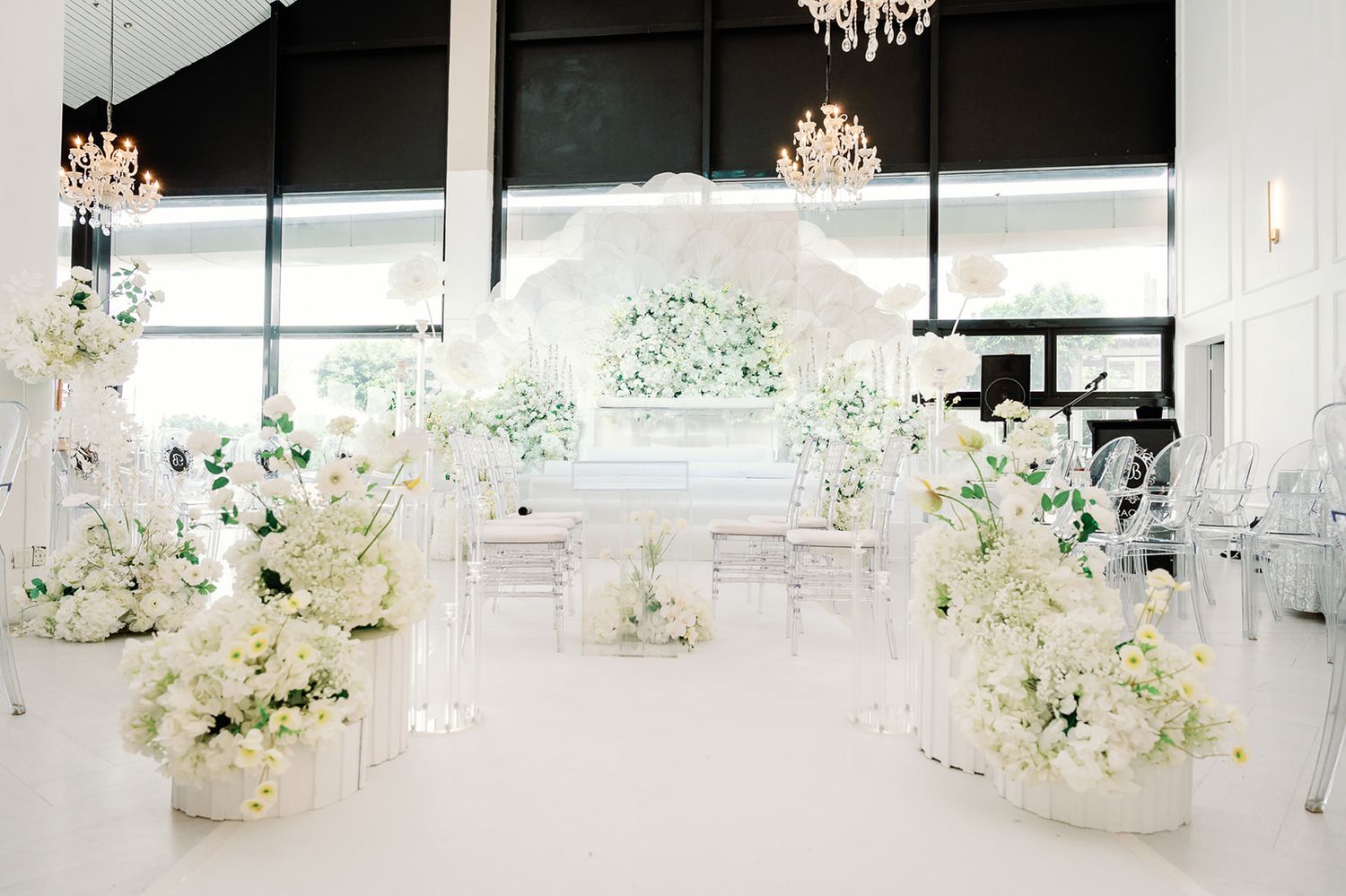 Stunning all-white Islamic wedding ceremony venue with floral arrangements and chandelier.