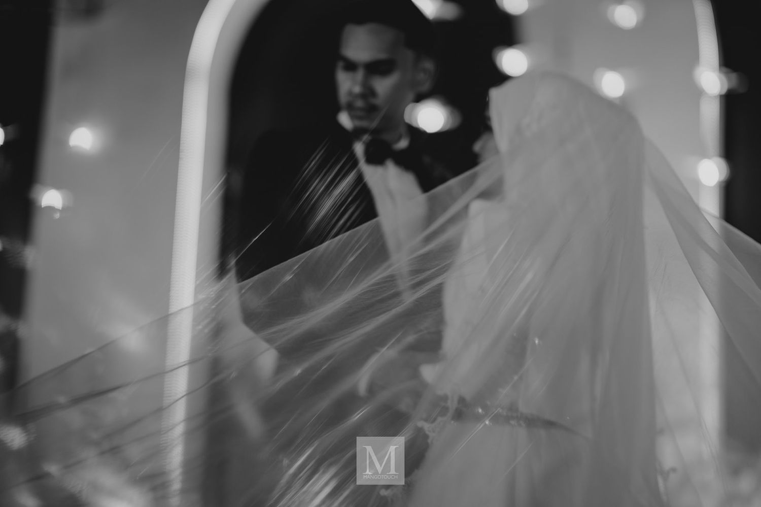 Black and white double exposure of bride and groom through car window at night.