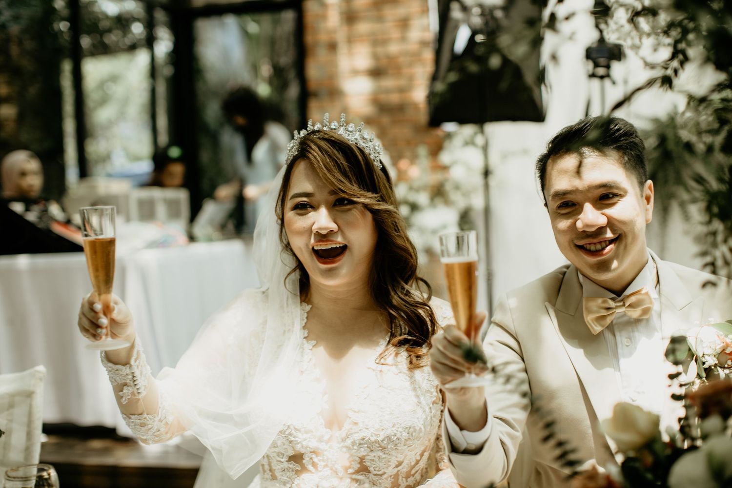 Happy bride and groom toast with champagne glasses during their wedding reception celebration.