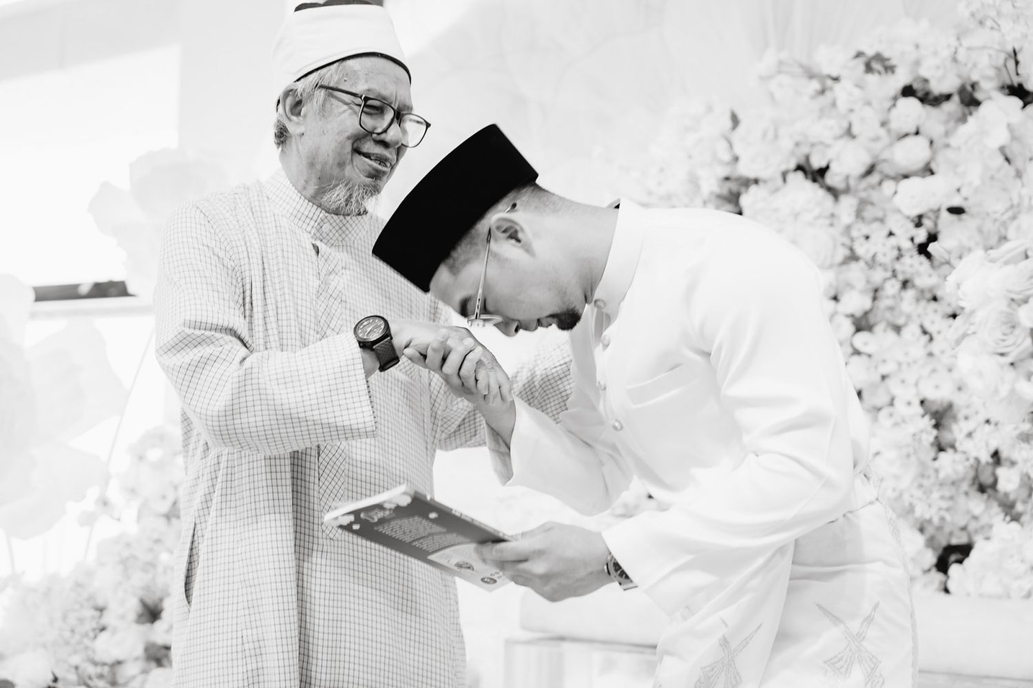 Akram is kissing the elder's hand at a formal ceremony which is Yang Berbahagia Dato' Seri Dr. Haji Zulkifli Mohamad Al-Bakri