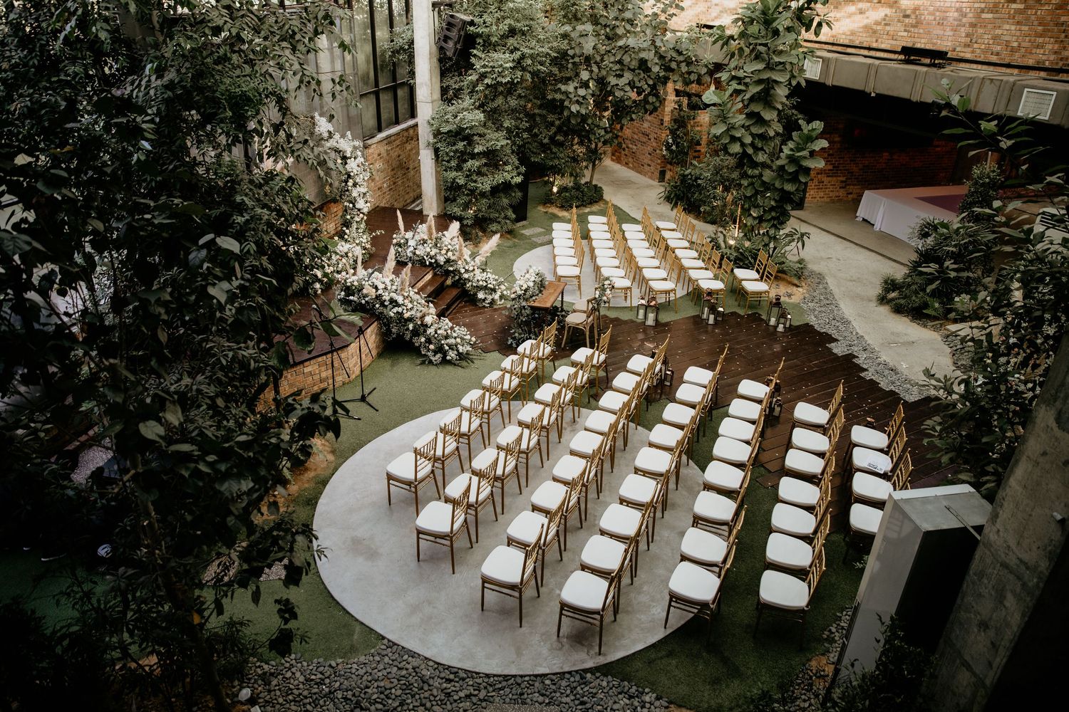 Aerial view of intimate greenhouse wedding ceremony setup with gold chairs arranged in neat rows.