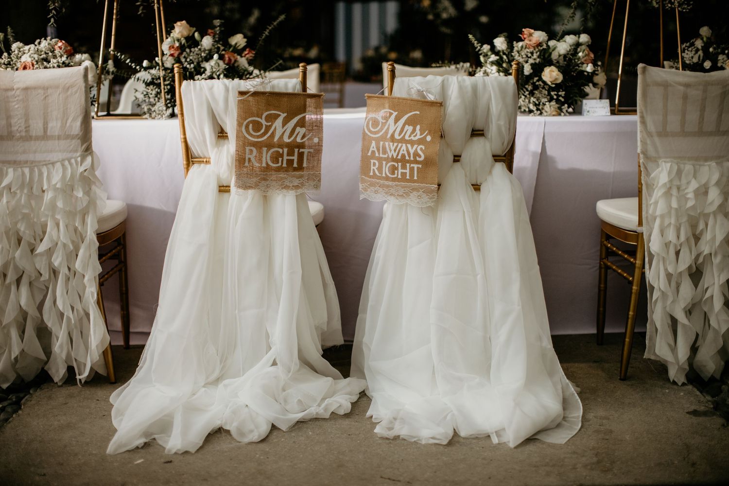 Mr. Right and Mrs. Always Right decorative signs on white tulle-draped wedding chairs at reception.