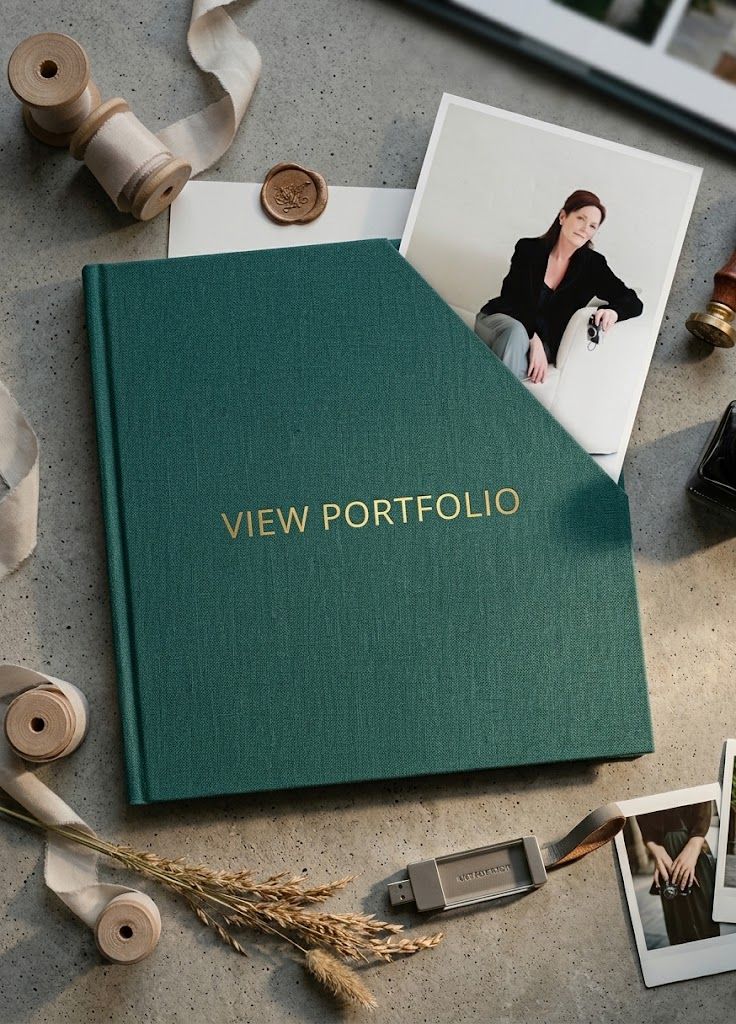 Green hardcover portfolio book with gold VIEW PORTFOLIO text surrounded by ribbons and photos.