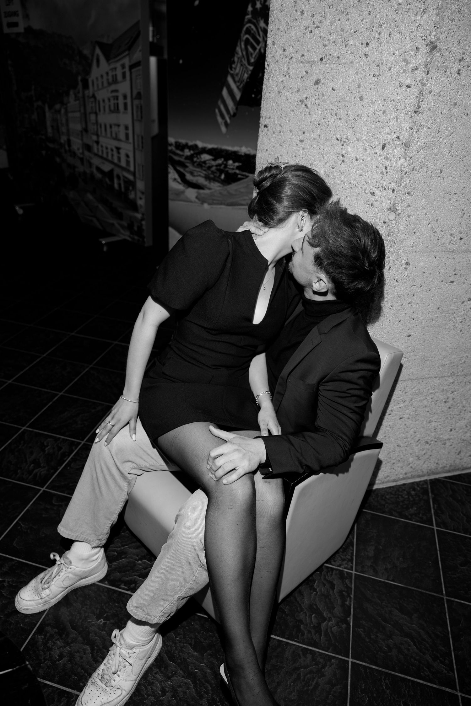Black and white image of a couple sharing an intimate kiss in a modern interior.