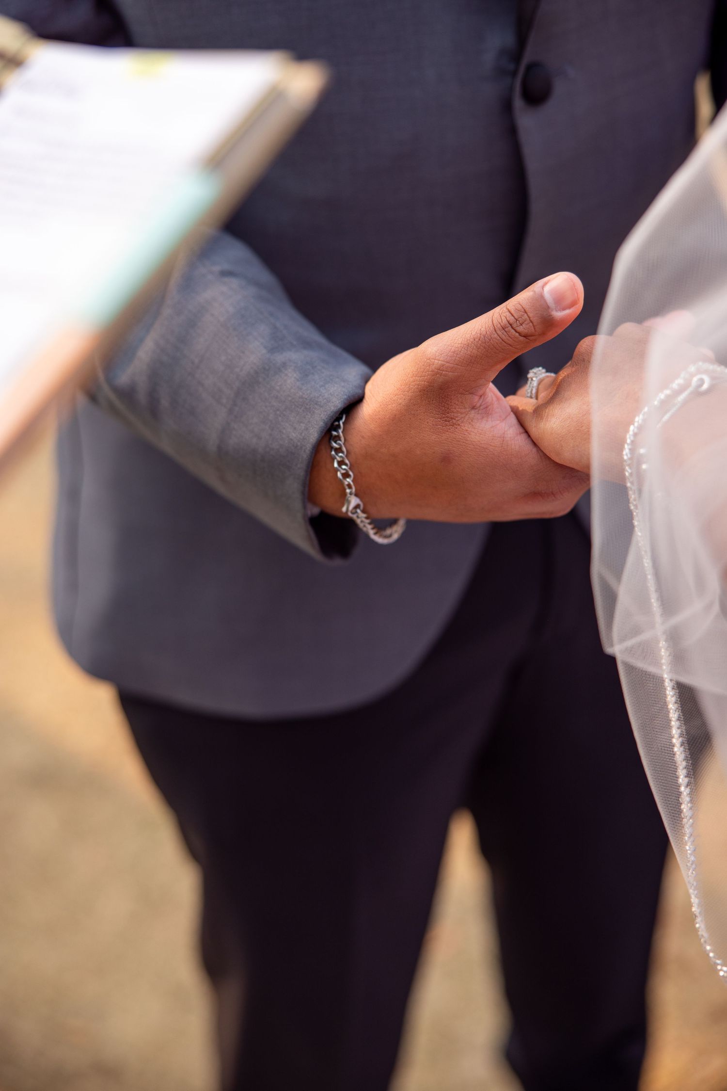 Detail shot of formal attire and hands during a wedding ceremony exchange.