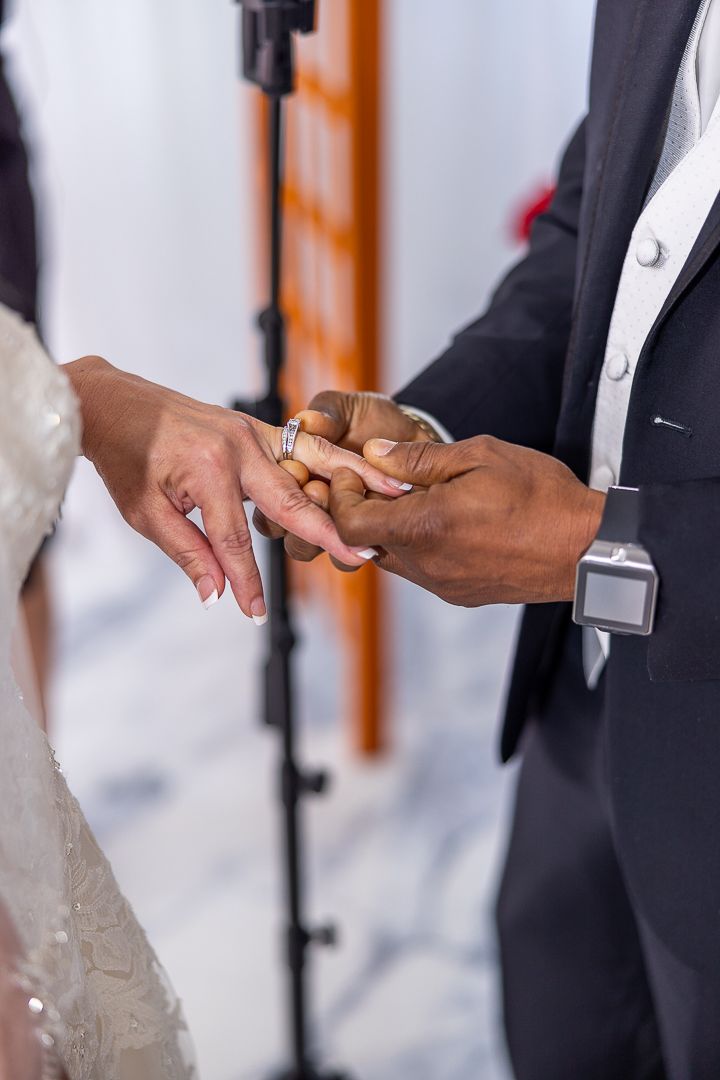 Close-up of hands exchanging wedding rings during the ceremony.