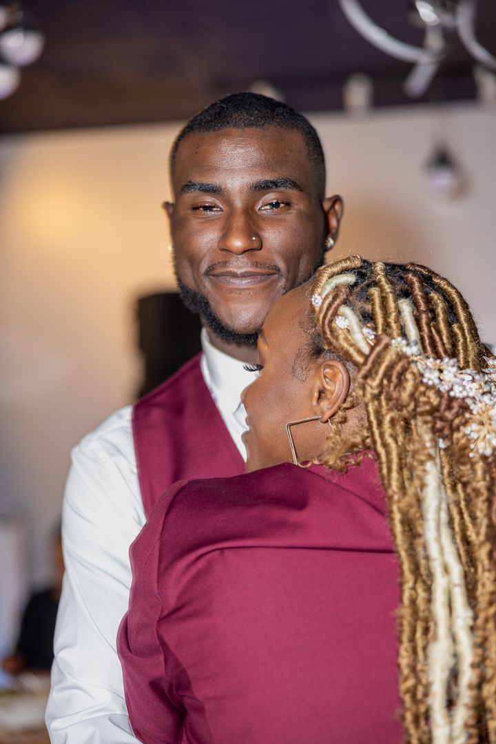A romantic moment captured during a wedding reception with burgundy and white attire.