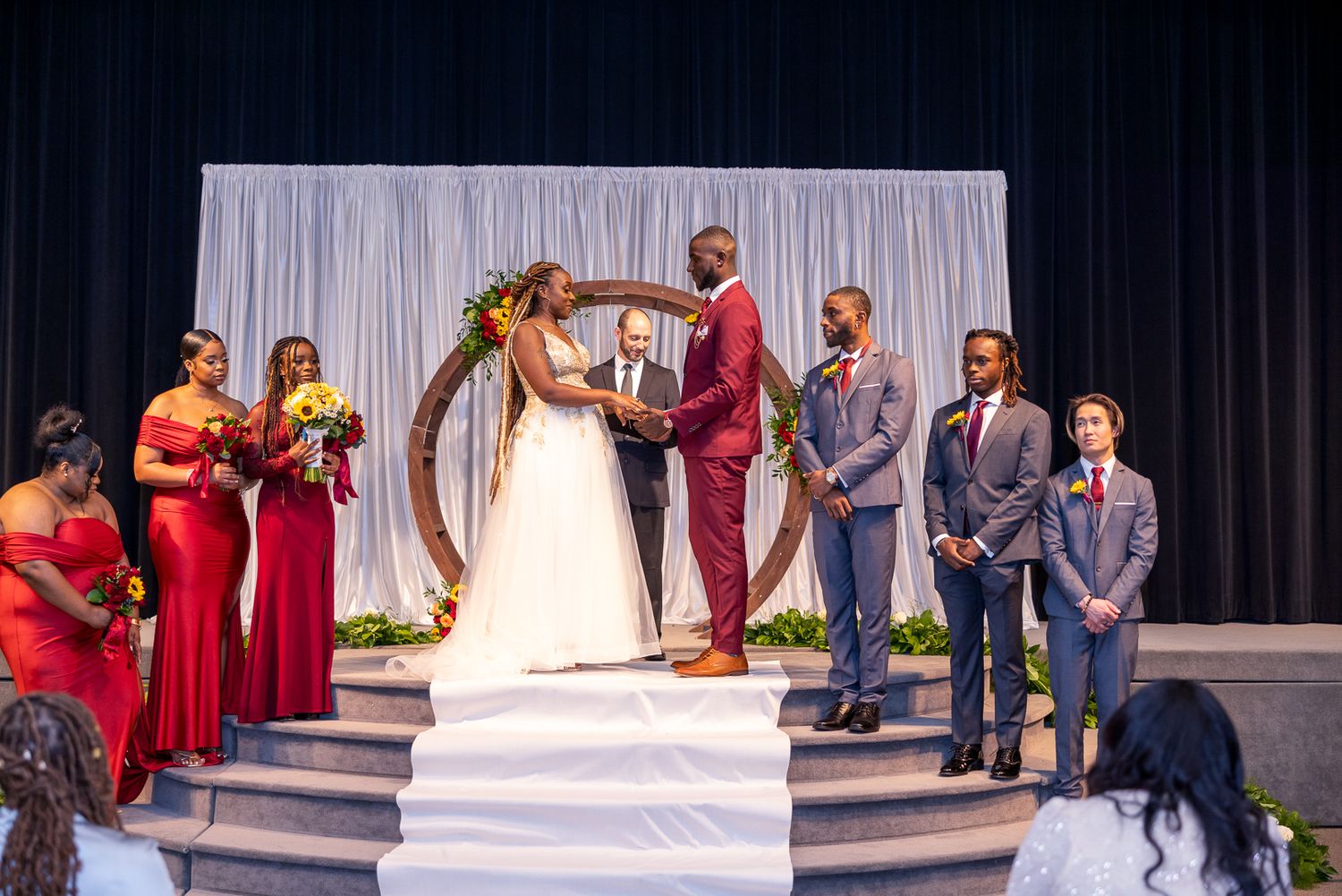Wedding ceremony space with white backdrop and guests seated in rows.